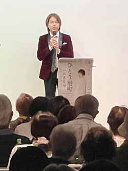ベトナム出身の歌手 タンロンさんがステージ上でマイクを持ちトークをしている様子