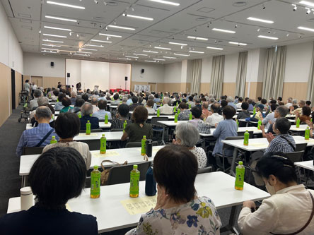 会場の様子。数百名の参加者がステージを見ながら座っています