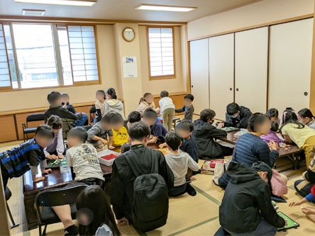 和室で大勢の子供たちがオセロなどのゲームを楽しんでいます。